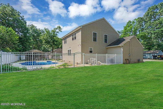 rear view of house featuring a fenced in pool and a lawn