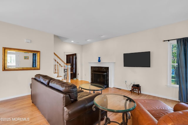 living room featuring light hardwood / wood-style floors, a wealth of natural light, and a high end fireplace