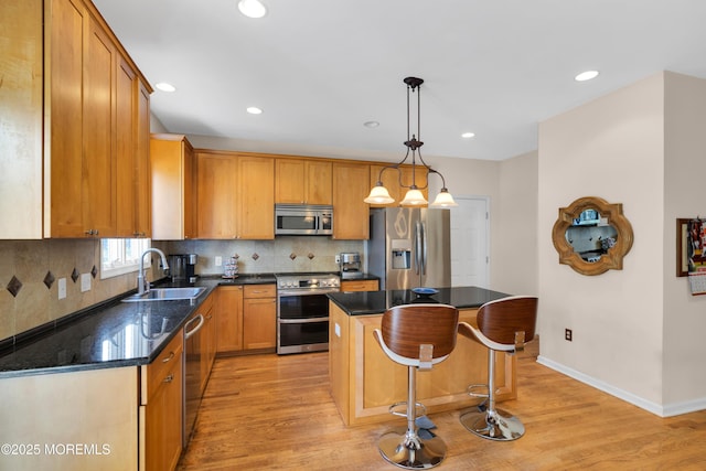 kitchen featuring appliances with stainless steel finishes, decorative backsplash, decorative light fixtures, a kitchen island, and sink