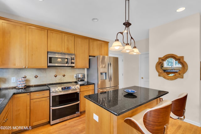 kitchen with stainless steel appliances, decorative backsplash, light wood-type flooring, hanging light fixtures, and a center island