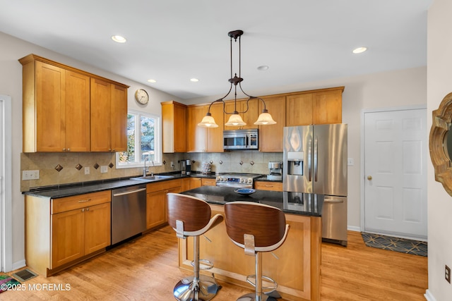 kitchen with a center island, sink, light hardwood / wood-style flooring, hanging light fixtures, and appliances with stainless steel finishes