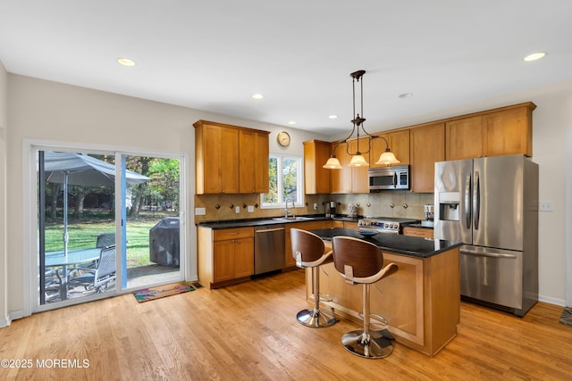 kitchen featuring a center island, light hardwood / wood-style floors, pendant lighting, sink, and appliances with stainless steel finishes