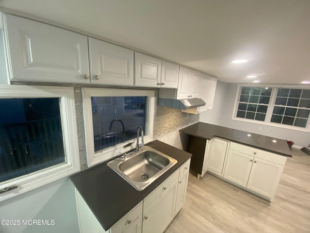 kitchen with white cabinetry, sink, backsplash, and light wood-type flooring