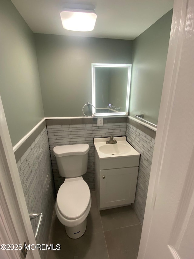 bathroom featuring tile walls, vanity, tile patterned flooring, and toilet