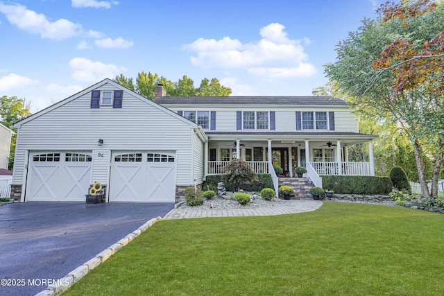 view of front of house featuring a front yard, ceiling fan, covered porch, and a garage