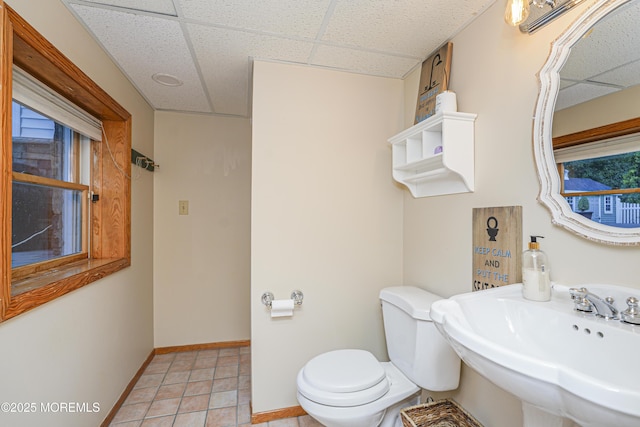 bathroom featuring toilet, a paneled ceiling, sink, and tile patterned flooring