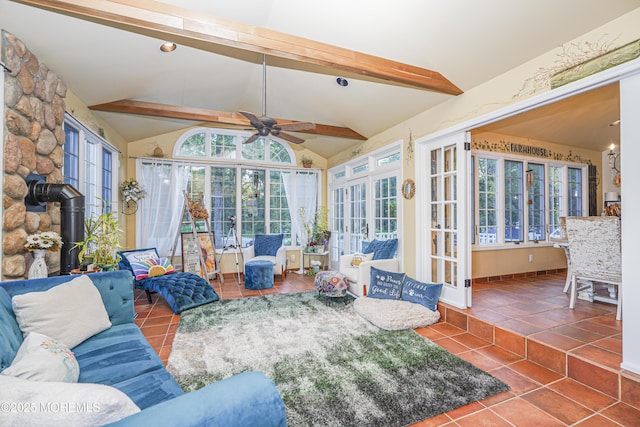 sunroom / solarium featuring ceiling fan, lofted ceiling, a wood stove, and plenty of natural light