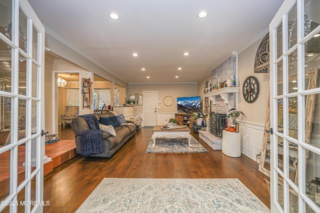 living room featuring dark wood-type flooring, french doors, a fireplace, and crown molding