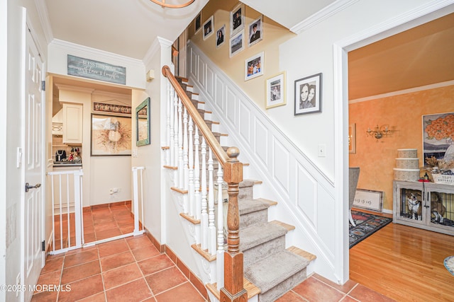 staircase with ornamental molding and tile patterned flooring