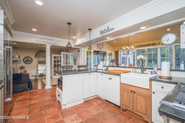 kitchen featuring ornate columns, white cabinets, hanging light fixtures, and sink