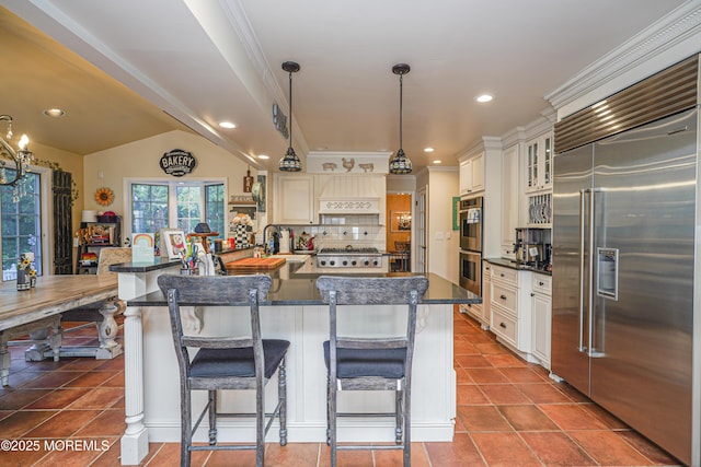 kitchen with vaulted ceiling, pendant lighting, a breakfast bar, decorative backsplash, and appliances with stainless steel finishes