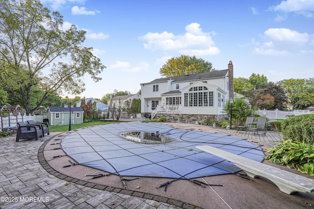 view of pool with a shed and a patio area