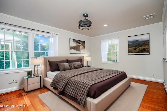 bedroom featuring hardwood / wood-style flooring, multiple windows, and crown molding