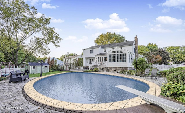 view of pool featuring a storage shed, a diving board, and a patio