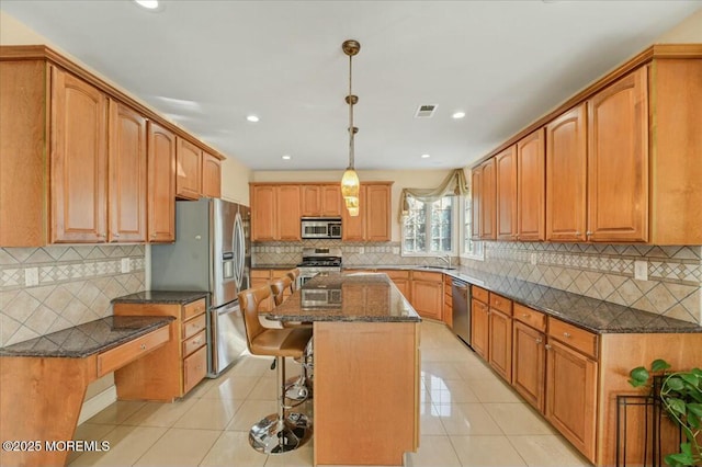 kitchen featuring pendant lighting, a kitchen island, stainless steel appliances, light tile patterned flooring, and a breakfast bar area