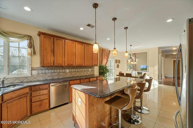 kitchen with stainless steel appliances, backsplash, a kitchen island, pendant lighting, and sink