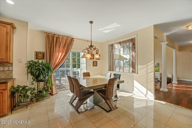 tiled dining room featuring ornate columns, plenty of natural light, and a notable chandelier