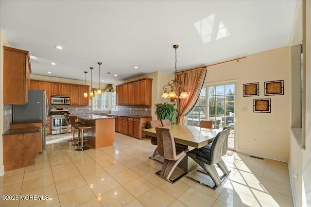 tiled dining space featuring a wealth of natural light, a chandelier, and sink