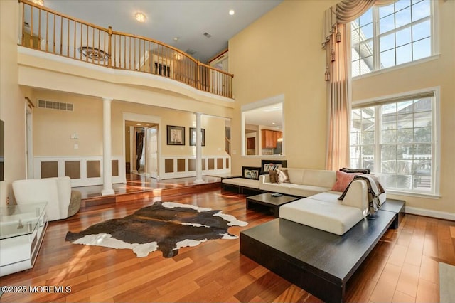 living room featuring decorative columns, hardwood / wood-style floors, and a towering ceiling