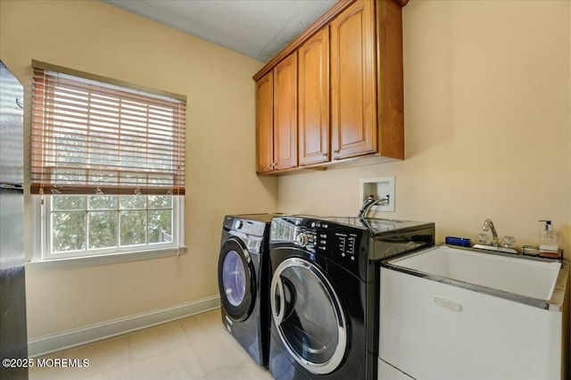 clothes washing area featuring washer and dryer, cabinets, and sink