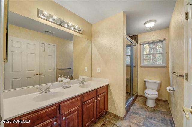 bathroom with a shower with shower door, toilet, and vanity