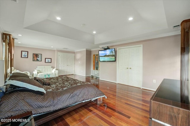 bedroom with crown molding, a closet, a raised ceiling, and hardwood / wood-style floors