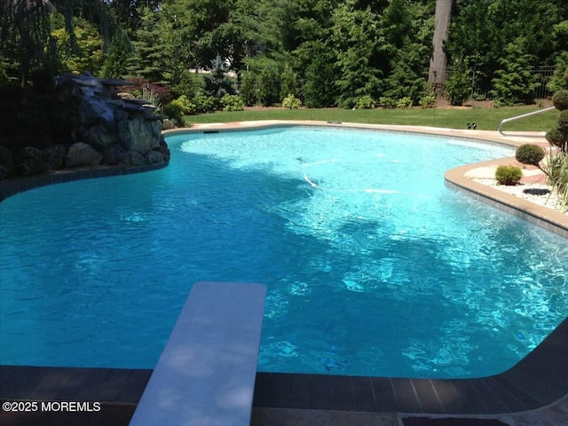 view of swimming pool with a diving board