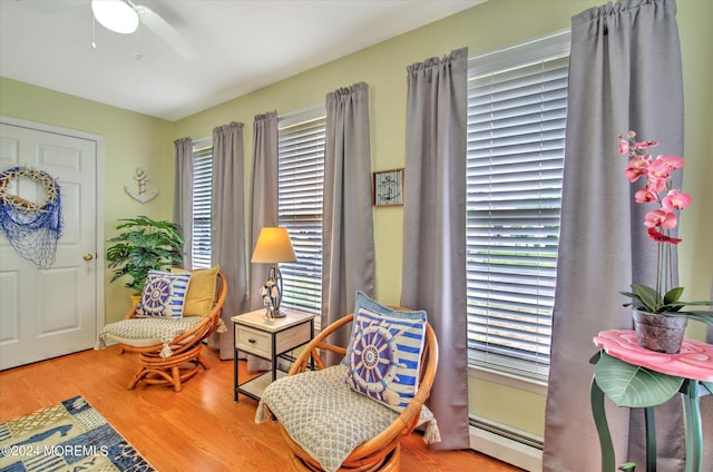 sitting room with hardwood / wood-style flooring, a baseboard heating unit, and ceiling fan