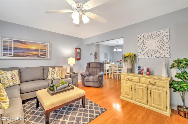 living room with light wood-type flooring and ceiling fan with notable chandelier