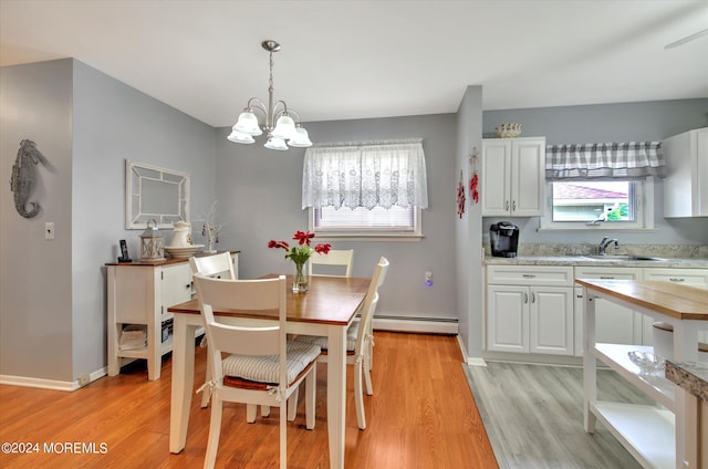 dining space featuring sink, a baseboard heating unit, light hardwood / wood-style flooring, and an inviting chandelier