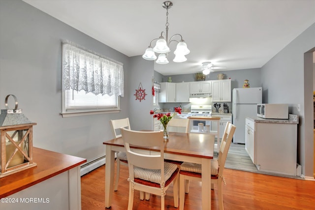 dining space with ceiling fan with notable chandelier, a baseboard radiator, and light hardwood / wood-style flooring