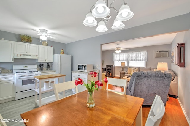 dining space featuring ceiling fan with notable chandelier, light hardwood / wood-style flooring, and a wall mounted AC