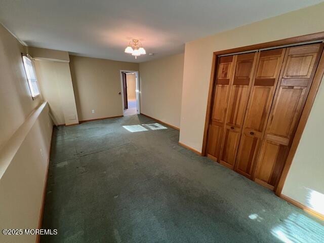 carpeted empty room featuring an inviting chandelier