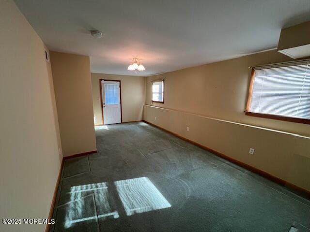 carpeted empty room featuring a notable chandelier