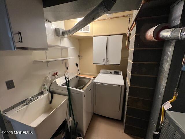 clothes washing area with cabinets, sink, and independent washer and dryer