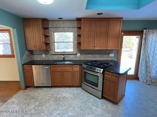 kitchen with light wood-type flooring, appliances with stainless steel finishes, a raised ceiling, and sink