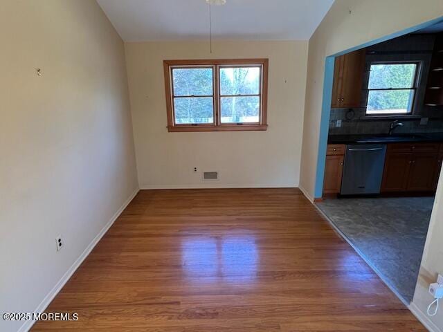 unfurnished dining area featuring vaulted ceiling and dark hardwood / wood-style floors