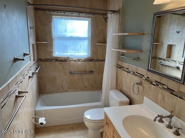 full bathroom featuring tile patterned flooring, vanity, tile walls, toilet, and shower / tub combo with curtain