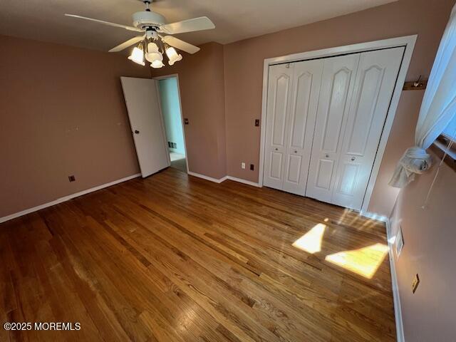 unfurnished bedroom with ceiling fan, a closet, and hardwood / wood-style flooring