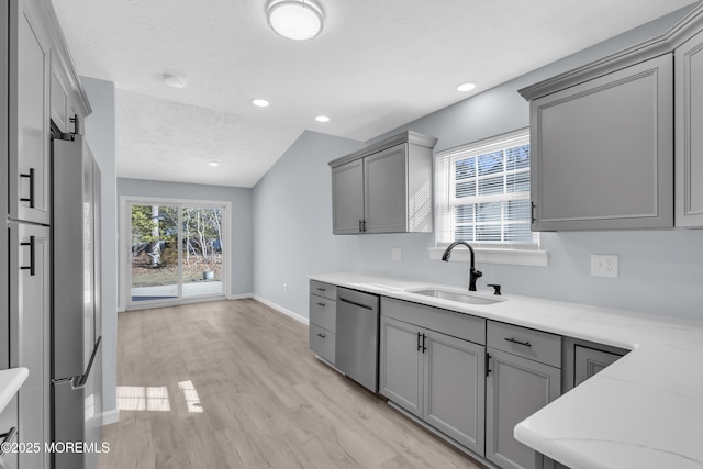 kitchen featuring lofted ceiling, sink, gray cabinetry, stainless steel appliances, and light hardwood / wood-style flooring