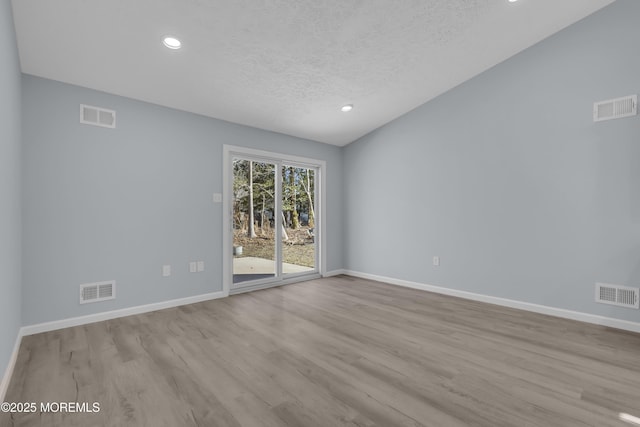 empty room with a textured ceiling and light wood-type flooring