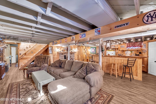 living room featuring bar area, wood walls, and hardwood / wood-style flooring