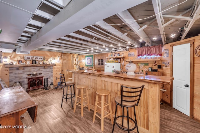 bar with hardwood / wood-style flooring, a wood stove, wood walls, and wooden counters