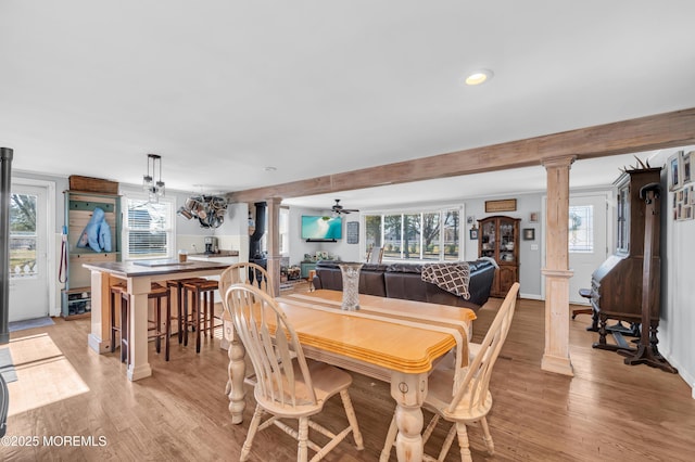 dining area featuring light wood-type flooring, ceiling fan, a healthy amount of sunlight, and decorative columns