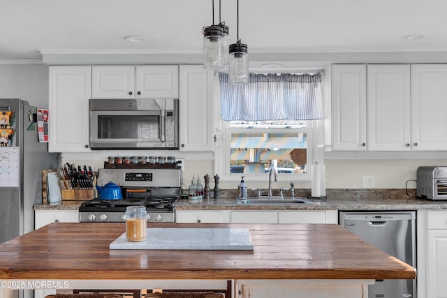 kitchen featuring white cabinetry, wooden counters, stainless steel appliances, decorative light fixtures, and sink