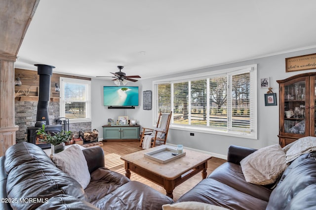 living room with ceiling fan, a healthy amount of sunlight, a wood stove, and hardwood / wood-style floors