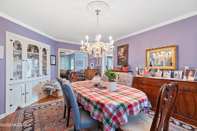 dining area with hardwood / wood-style floors, crown molding, and a chandelier