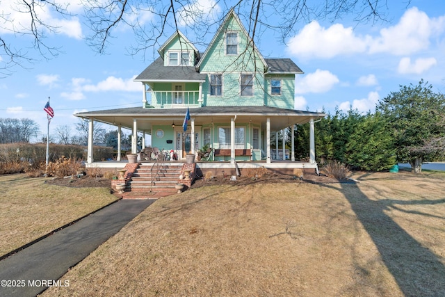 view of front of home featuring a balcony, a porch, and a front yard