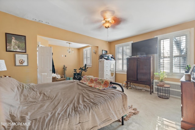 bedroom with ceiling fan with notable chandelier, light colored carpet, and radiator heating unit