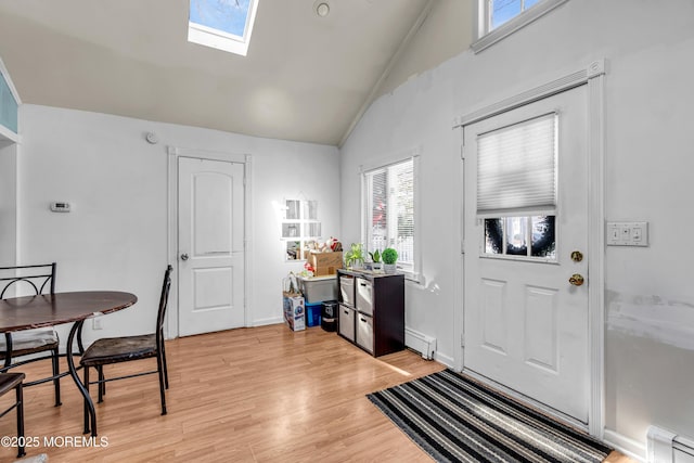 foyer with light hardwood / wood-style flooring, baseboard heating, and vaulted ceiling with skylight